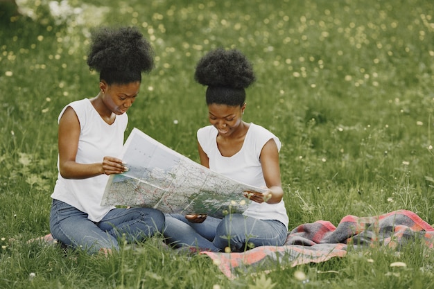 Twee Afro-Amerikaanse zusters die op een kaart in een park kijken