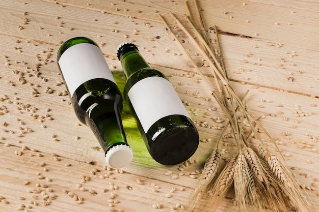 Twee alcoholische flessen en oren van tarwe op houten oppervlak