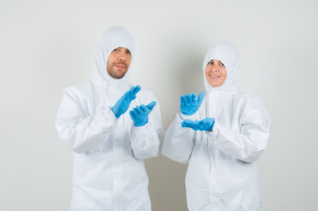 Twee artsen in beschermende pakken, handschoenen applaudisseren en op zoek gelukkig