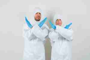 Gratis foto twee artsen in beschermende pakken, handschoenen die stopgebaar tonen en resoluut kijken