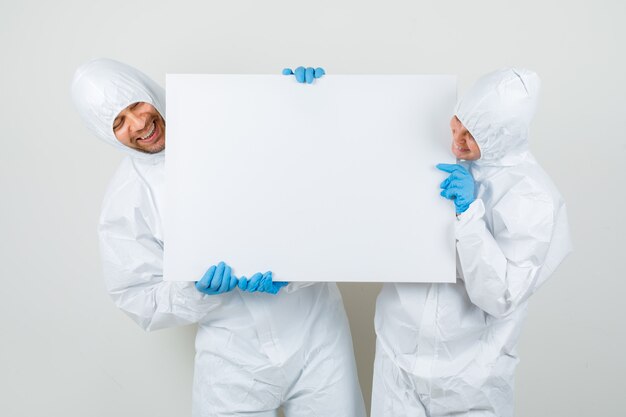 Twee artsen in beschermende pakken, handschoenen met een leeg canvas en op zoek vrolijk