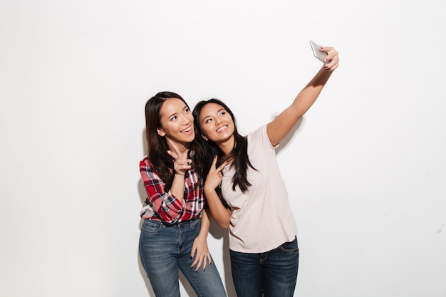 Twee Aziatische vrolijke positieve dames zusjes maken selfie