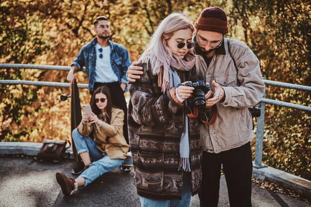 Twee beste vrienden kijken naar foto's op de fotocamera terwijl ze genieten van een wandeling in het herfstpark.