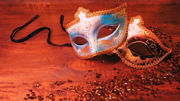 Twee blauw en gouden carnaval masker met glinsterende pailletten op houten bureau