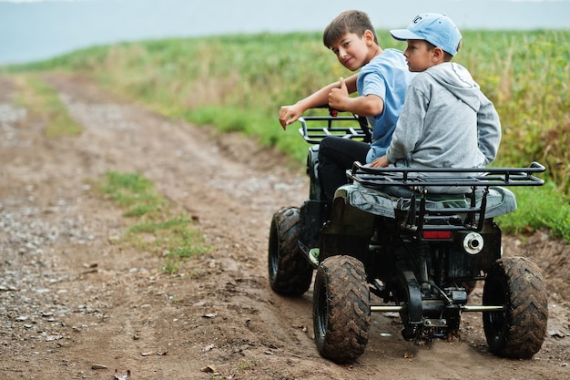 Twee broers die een quad quad met vierwielaandrijving rijden Gelukkige kindermomenten