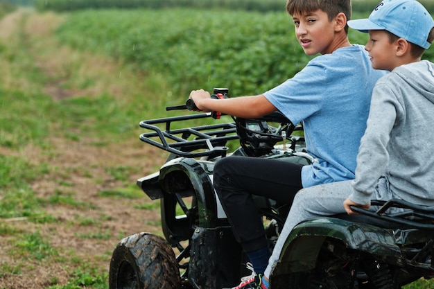 Twee broers die een quad quad met vierwielaandrijving rijden Gelukkige kindermomenten