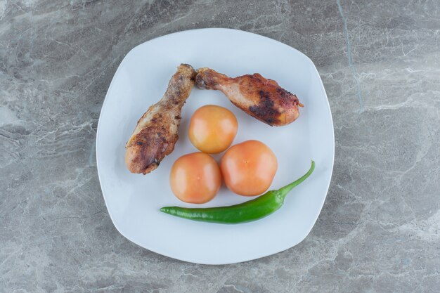 Twee gegrilde kippenboutjes met tomaat en peper.