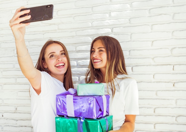 Twee gelukkige jonge vrouwen die selfie op smartphone nemen