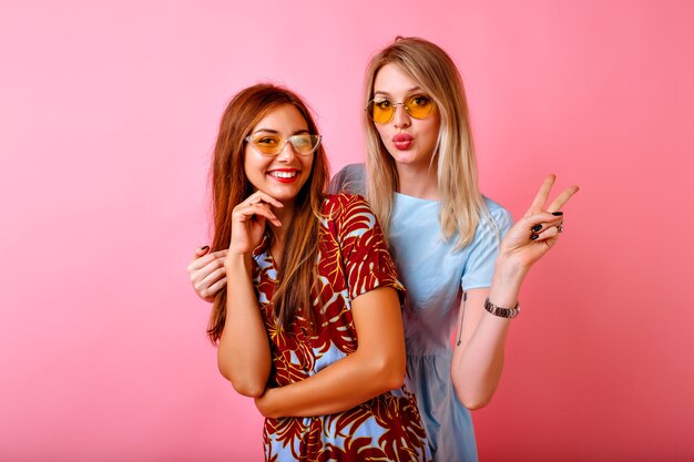 Twee gelukkige mooie zusters beste vrienden hipster vrouwen samen plezier op roze studio achtergrond