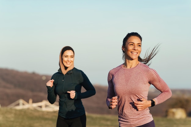 Twee gelukkige sportvrouwen genieten tijdens het joggen in de ochtend in de natuur