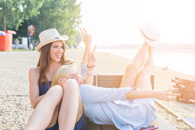 Twee gelukkige vrouwelijke vrienden die bij strand genieten van