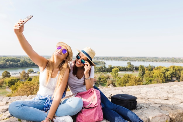 Twee gelukkige vrouwelijke vrienden die selfie op cellphone nemen