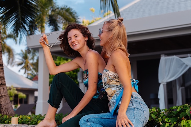 Twee gelukkige vrouwenvrienden met zonnebril op vakantie in tropisch land