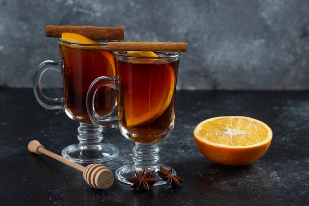 Twee glazen bekers met lekkere thee en kaneelstokjes.