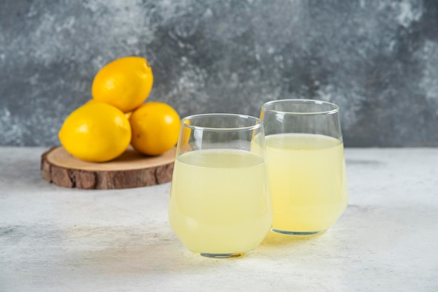 Twee glazen kopjes limonade met citroenen.