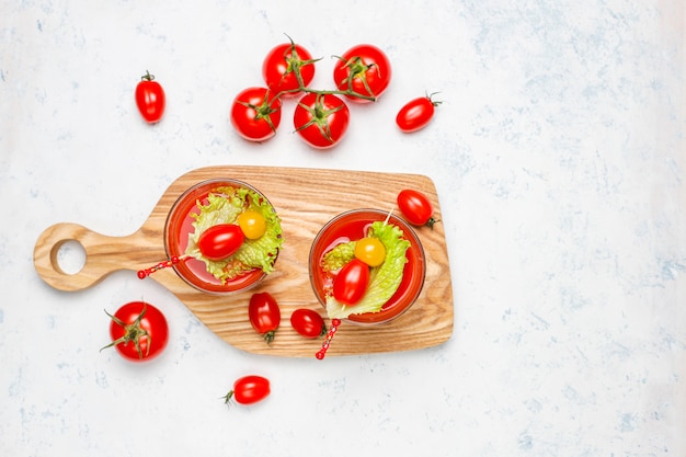 Twee glazen vers tomatesap en tomaten op grijze concrete oppervlakte