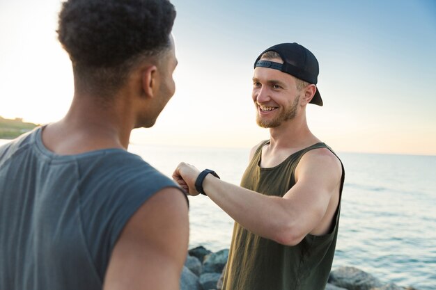 Twee glimlachende sportmannen die na het runnen van training rusten