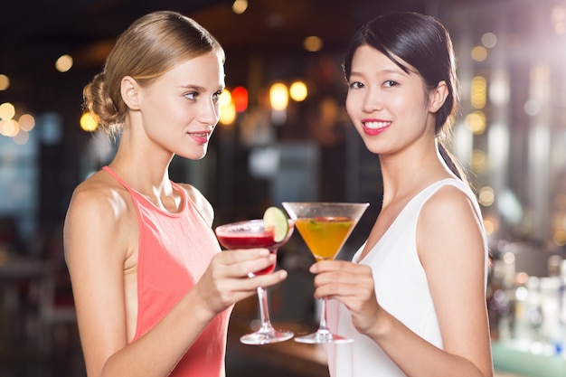 Twee glimlachende vrouwen met cocktails in restaurant