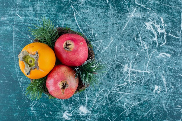 Twee granaatappels met kaki op marmer.