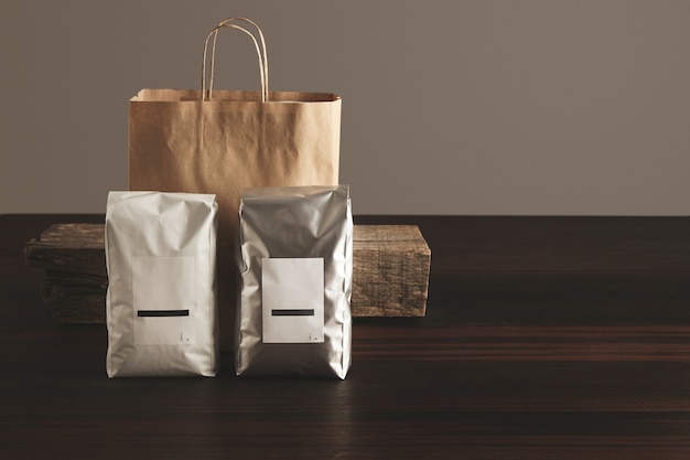 Twee grote hermetische pakketten met blanco etiketten gepresenteerd voor ambachtelijke papieren zak en rustieke houten baksteen op rode tafel