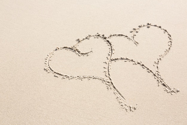 Twee hart vormen getrokken op zand