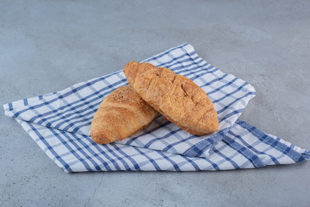 Twee heerlijke zoete croissants met tafelkleed op steen.