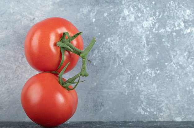 Twee hele verse, sappige tomaten op grijs.