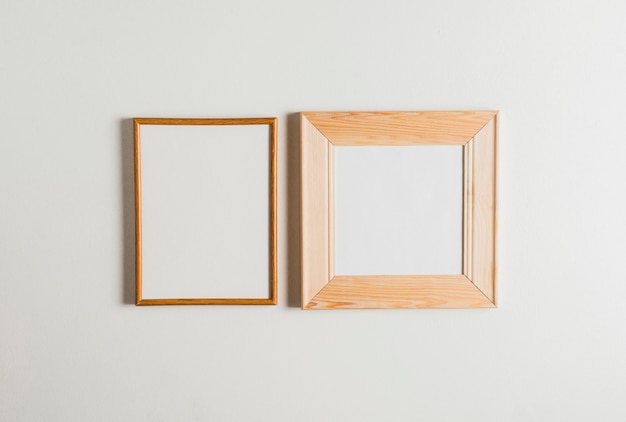 Gratis foto twee houten kaders die op witte muur hangen