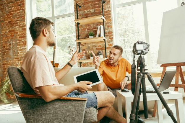 Twee jonge blanke mannelijke bloggers in vrijetijdskleding met professionele apparatuur