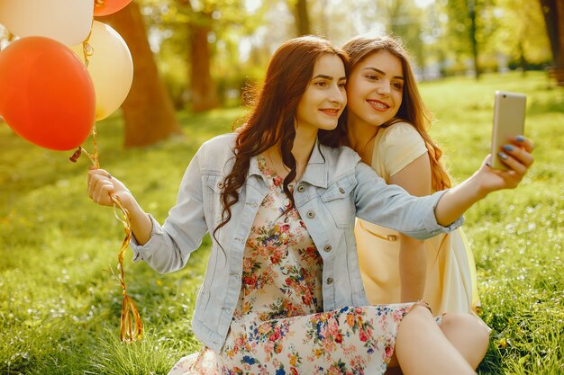 twee jonge en heldere meisjes brengen hun tijd door in het zomerpark met ballonnen