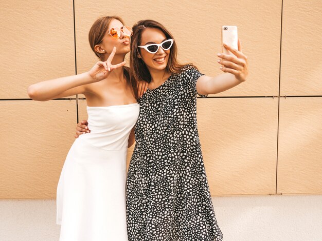 Twee jonge glimlachende hipster vrouwen in de zomerkleren.