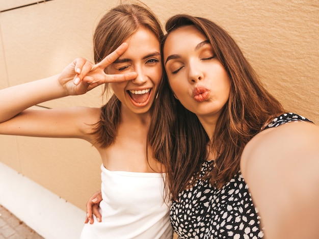 Twee jonge glimlachende hipster vrouwen in de zomerkleren.