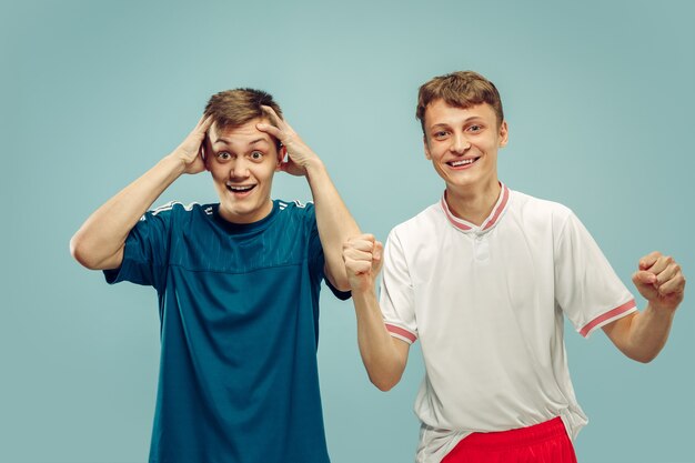 Twee jonge mannen die zich in sportkleding bevinden die op blauw worden geïsoleerd