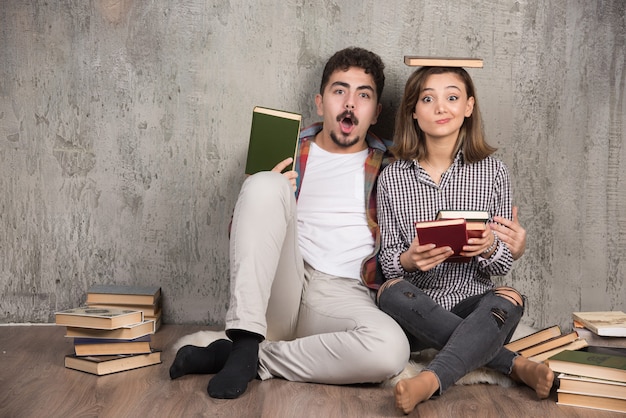 Twee jonge mensen poseren met een heleboel boeken