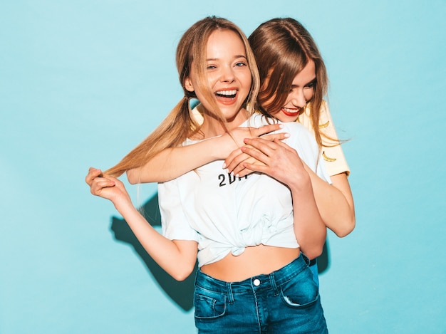 Twee jonge mooie glimlachende blonde hipstermeisjes in kleren van de trendy de zomer kleurrijke t-shirt.