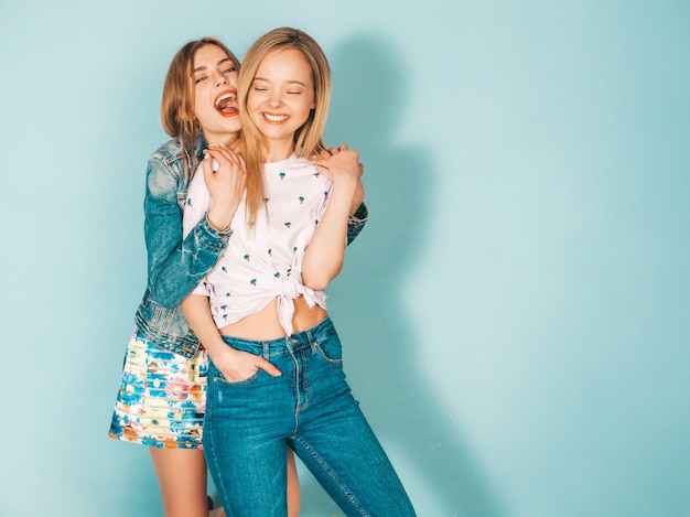 Twee jonge mooie glimlachende blonde hipstermeisjes in trendy de zomer kleurrijke kleren.