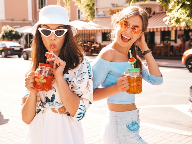 Twee jonge mooie glimlachende hipster meisjes in trendy zomer kleding en panama hoed.