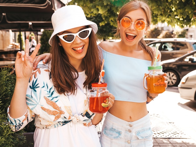 Gratis foto twee jonge mooie glimlachende hipster meisjes in trendy zomer kleding en panama hoed.