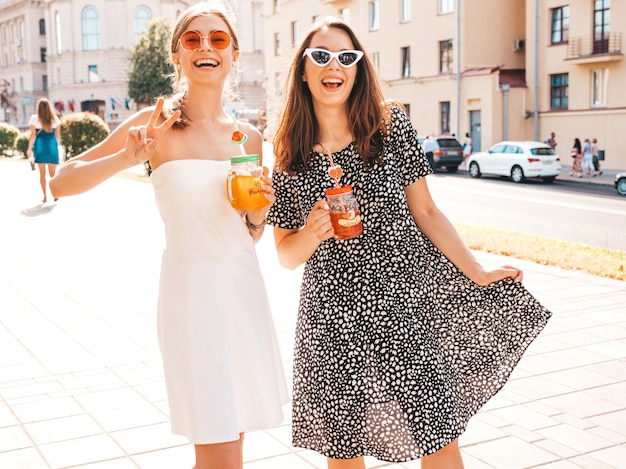 Twee jonge mooie glimlachende hipster meisjes in trendy zomerkleren