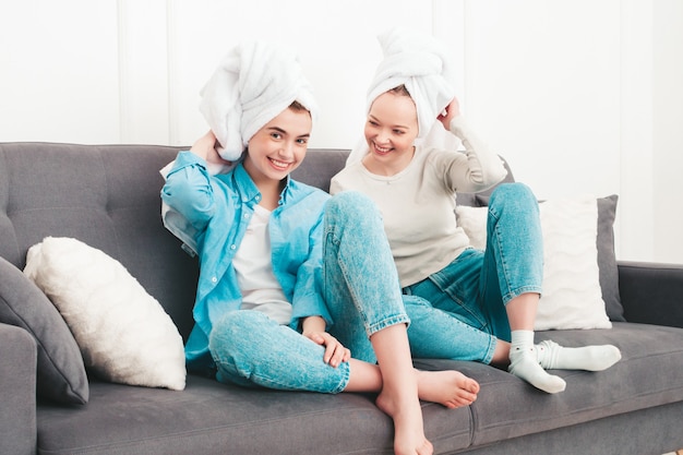 Twee jonge mooie glimlachende vrouwen die bij de bank zitten