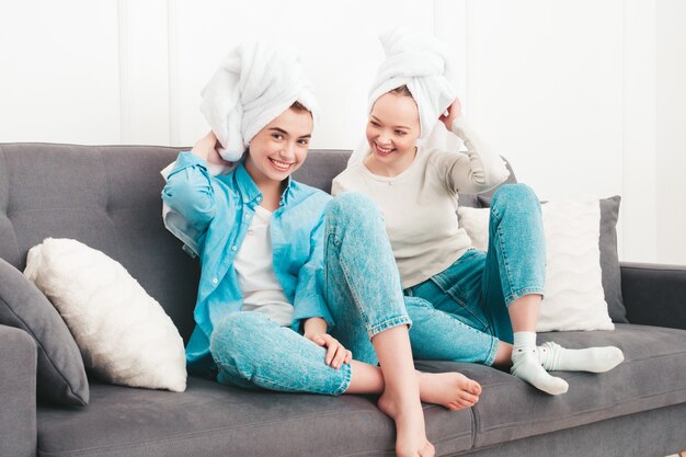 Twee jonge mooie glimlachende vrouwen die bij de bank zitten