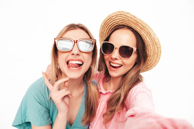 Twee jonge mooie lachende brunette hipster vrouw in trendy zomerjurken Sexy zorgeloze vrouwen poseren in de buurt van witte muur Positieve modellen plezier vrolijk en gelukkig Pov selfie foto's maken