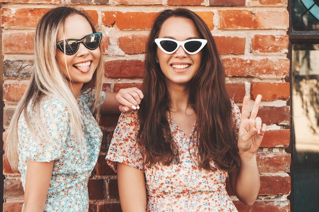 Twee jonge mooie lachende hipster vrouw in trendy zomerjurkenSexy zorgeloze vrouwen poseren in de straat Positieve pure modellen plezier bij zonsondergang knuffelen en gek worden