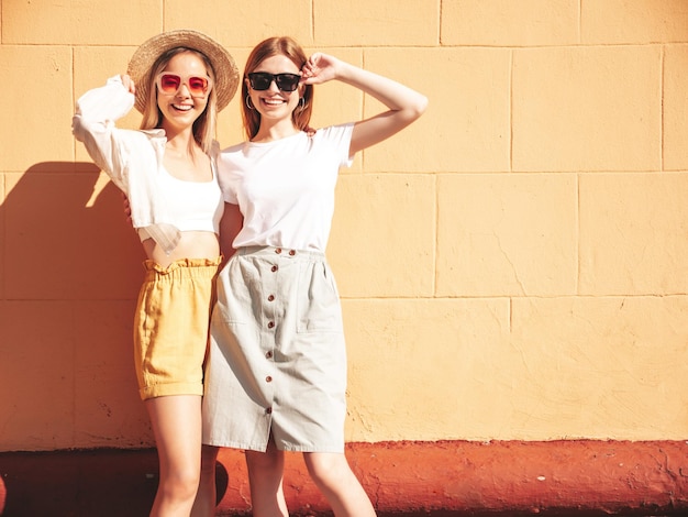 Twee jonge mooie lachende hipster vrouw in trendy zomerkleren sexy zorgeloze vrouwen poseren in de straat in hoed positieve pure modellen plezier bij zonsondergang