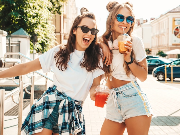Twee jonge mooie lachende hipster vrouwen in trendy zomerkleren