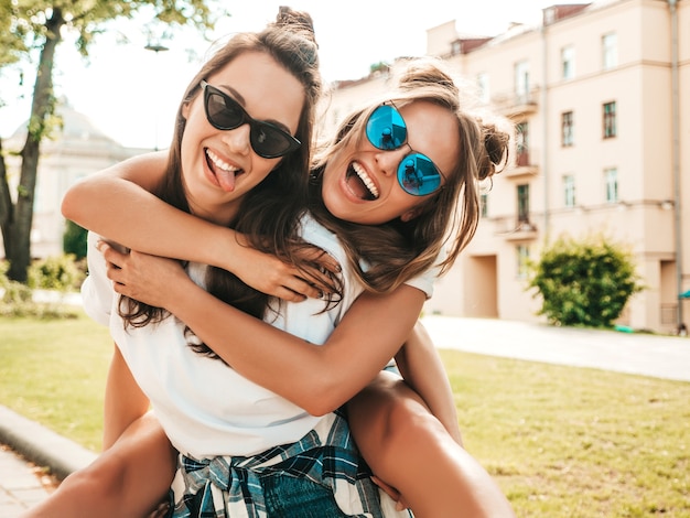Twee jonge mooie lachende hipster-vrouwen in trendy zomerse witte t-shirtkleren