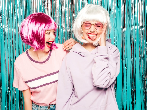 Twee jonge sexy hipster meisjes in pruiken en rode lippen. mooie trendy vrouwen in zomer kleding plezier