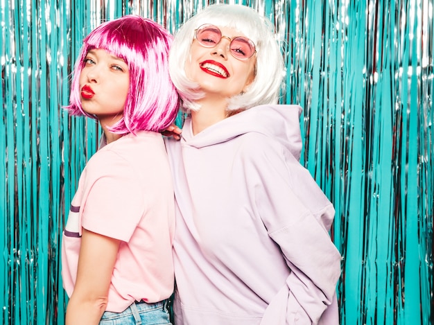 Twee jonge sexy hipster meisjes in pruiken en rode lippen. Mooie trendy vrouwen in zomer kleding plezier