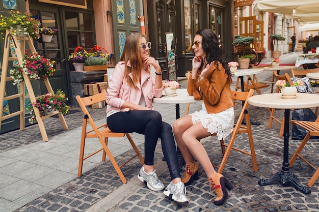 Twee jonge stijlvolle vrouwen zitten in café