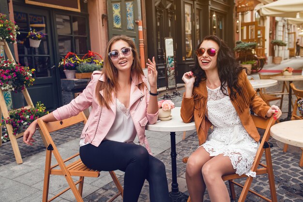 Twee jonge stijlvolle vrouwen zitten in café